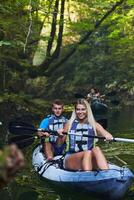 A group of friends enjoying having fun and kayaking while exploring the calm river, surrounding forest and large natural river canyons photo