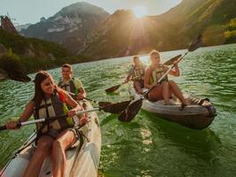 A group of friends enjoying fun and kayaking exploring the calm river, surrounding forest and large natural river canyons during an idyllic sunset. photo