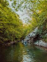 A group of friends enjoying having fun and kayaking while exploring the calm river, surrounding forest and large natural river canyons photo