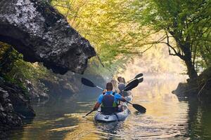 A group of friends enjoying having fun and kayaking while exploring the calm river, surrounding forest and large natural river canyons photo