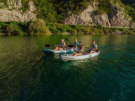 A group of friends enjoying fun and kayaking exploring the calm river, surrounding forest and large natural river canyons during an idyllic sunset. photo