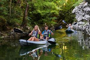 A group of friends enjoying having fun and kayaking while exploring the calm river, surrounding forest and large natural river canyons photo