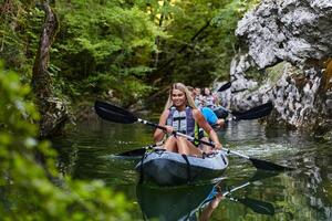 A group of friends enjoying having fun and kayaking while exploring the calm river, surrounding forest and large natural river canyons photo