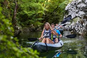 A group of friends enjoying having fun and kayaking while exploring the calm river, surrounding forest and large natural river canyons photo