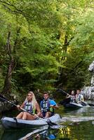 A group of friends enjoying having fun and kayaking while exploring the calm river, surrounding forest and large natural river canyons photo