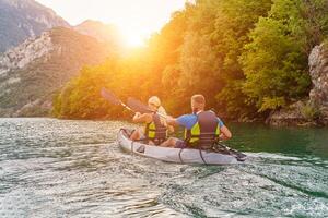 A group of friends enjoying fun and kayaking exploring the calm river, surrounding forest and large natural river canyons during an idyllic sunset. photo