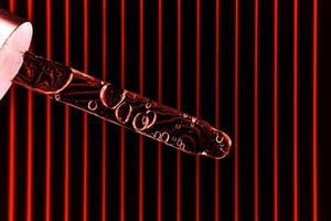 Serum in a pipette on a black and red ribbed background. photo