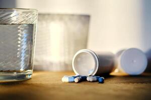 A glass of water and a bottle of pills in the sunlight. photo