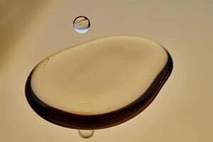 Texture of cosmetic oil with falling drop on golden background. photo