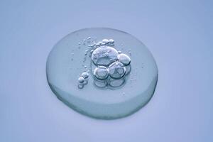 Textured round drop of serum with bubbles on dark blue background. photo