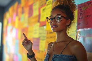Attractive woman with glasses pointing at colorful sticky notes on a wall for presentation ideas photo