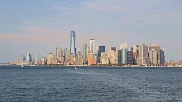 Panoramic view of Lower Manhattan skyline across the Hudson River, modern and historic skyscrapers glowing under soft daylight with boats on the water video