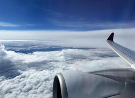 Aerial view of sky and clouds from above seen through the aircraft window, travelling by plane, magnificent breathtaking view during flight high through the cumulus clouds photo