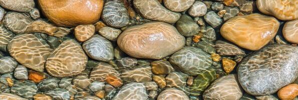 Riverbed stones under sunlight creating mesmerizing water patterns in nature photo