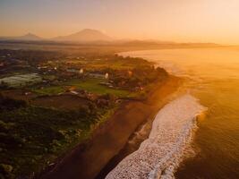 Drone view of beach coastline with Agung volcano with warm sunrise tones and ocean in Bali photo