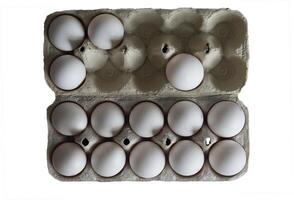 Tray with chicken eggs isolated on a white background. An open paper tray with chicken eggs that holds 14 white eggs. photo