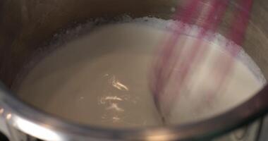 A whisk is being used to mix milk in a pot video