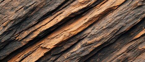 Weathered rock texture with layers showing deep cracks and natural erosion. The rugged stone surface displays geological details and earthy tones. photo