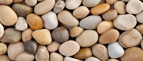 Mixed river pebbles close up showing various sizes and colors of smooth, rounded stones. The earthy tones and polished surfaces create a natural and organic background. photo