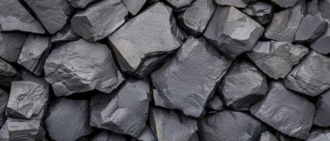 Dark crushed rocks close up texture showing rough, fractured surfaces with jagged edges. The irregular stone arrangement highlights a rugged and natural geological pattern. photo