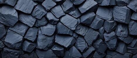 Black crushed rocks close up texture showing sharp, irregular shapes and rough surfaces. The dark stones create a rugged and natural pattern, emphasizing the raw, unpolished appearance. photo