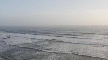 Aerial view of waves crashing on beach with distant horizon video