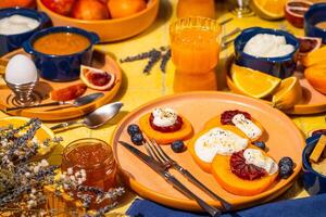 Sliced persimmon with ricotta, blood orange and honey, completing a colorful breakfast table setting photo