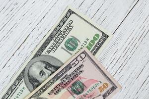 Bills of 100 and 50 dollars on white wooden background photo