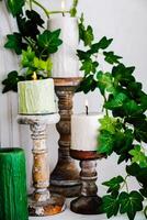 Elegant display of candles on rustic holders with greenery accents in cozy space photo