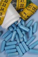 bottle of pills, some of which spilled into a light blue surface photo