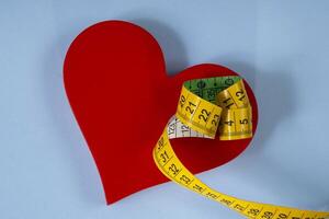 red heart shape with measuring tape symbolizing health care symbol photo