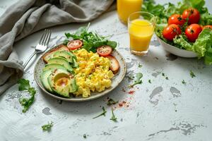 A plate of scrambled eggs and avocado toast, with a glass of orange juice on the side. photo