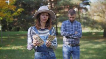 A wife counts her husband's money in the park. Concept of family relations video