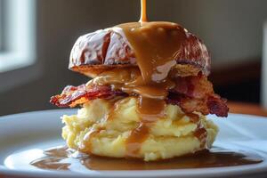 Delicious sandwich with melting cheddar cheese, crispy bacon, and flowing gravy served over mashed potatoes photo