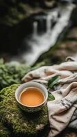 Ancient porcelain cup filled with amber tea rests on mossy stones by a stream in Chinas mountainous area at night photo