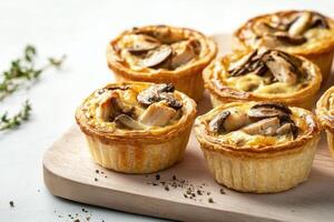 Mini chicken and mushroom quiches with flaky crust and creamy filling on rustic wooden board photo