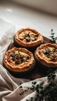 Mini chicken and mushroom quiches appear to float gracefully above a linen cloth, showcasing their golden crust and creamy filling photo