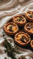 Mini chicken and mushroom quiches appear to float elegantly above a linen backdrop, showcasing their creamy filling and golden crust photo