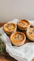 Mini chicken and mushroom quiches levitate gracefully above a soft linen cloth in a modern culinary setting photo