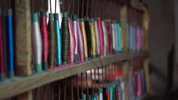 Costura, tradicional artesanía, de cerca de un hilo pandeo máquina en un textil Costura artesanía o natural vistoso hilos o hilo. video
