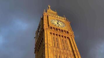 Big Ben in the heart of Westminster in London, illuminated at dusk, golden glow against a dramatic sky video