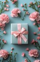 Elegant gift box with pink ribbon and carnations on pastel blue background photo