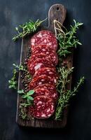Slices of Dried Salami with Spices and Herbs on Board photo