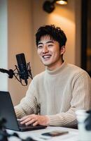 Korean man recording a podcast at desk with laptop photo