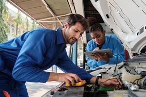 EV car check, mechanic workers coworker inspects and maintains service of electric engine and battery in fixed automobile garage station, professional technology transportation industry business. photo