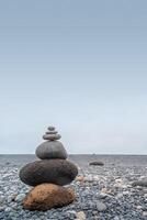 Cover page with view of a pyramid made of stack of round stones put together at each other at gravel beach seacoast copy space photo