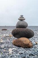 View of a pyramid made of stack of round stones put together at each other at stony gravel beach seacoast photo