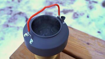 A kettle on a wooden table with snow on the ground video