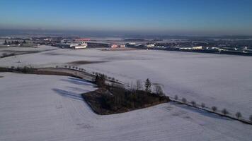 Aerial view of a snow covered field with a factory in the distance video