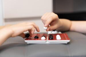 Family Fun at Home. Kids enjoy a game on the board with black and white marbles. The challenge keeps them focused as they laugh and play, creating fun memories at home. photo